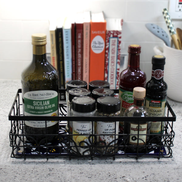 Temp-tations Metal Serving & Organizing Basket with Stoneware Trivet filled with cooking oils and spices on a kitchen counter