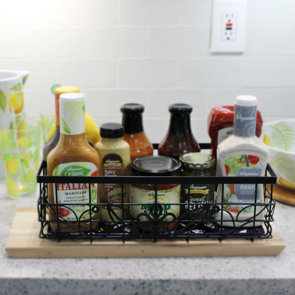 Temp-tations Metal Serving & Organizing Basket with Stoneware Trivet filled with bottles of salad dressing and condiments on the kitchen counter