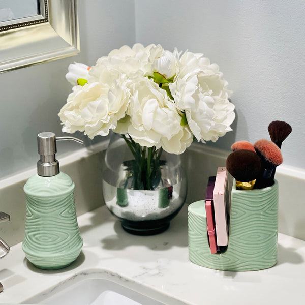 Temp-tations Essentials Soap Dispenser & Sponge Holder in Woodland Mint on a bathroom sink with makeup and flowers